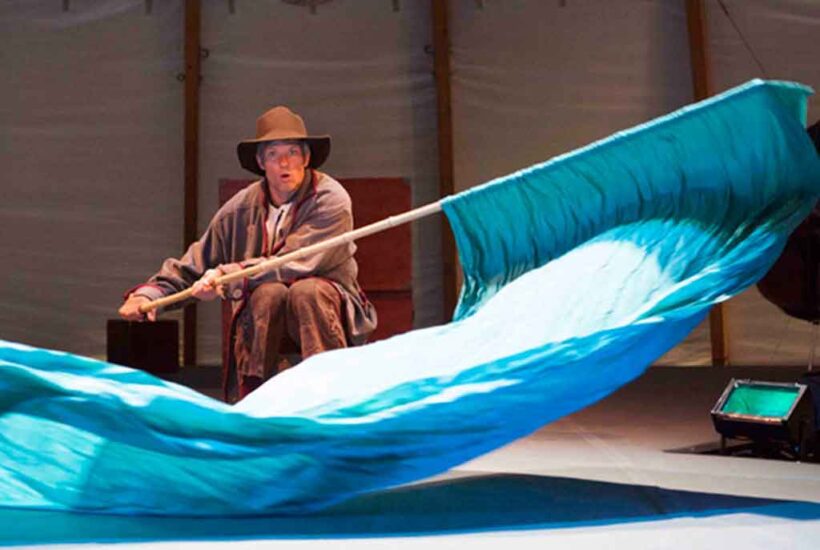 Un hombre ondea una tela azul de grandes dimensiones en el espectáculo El pescador y su mujer