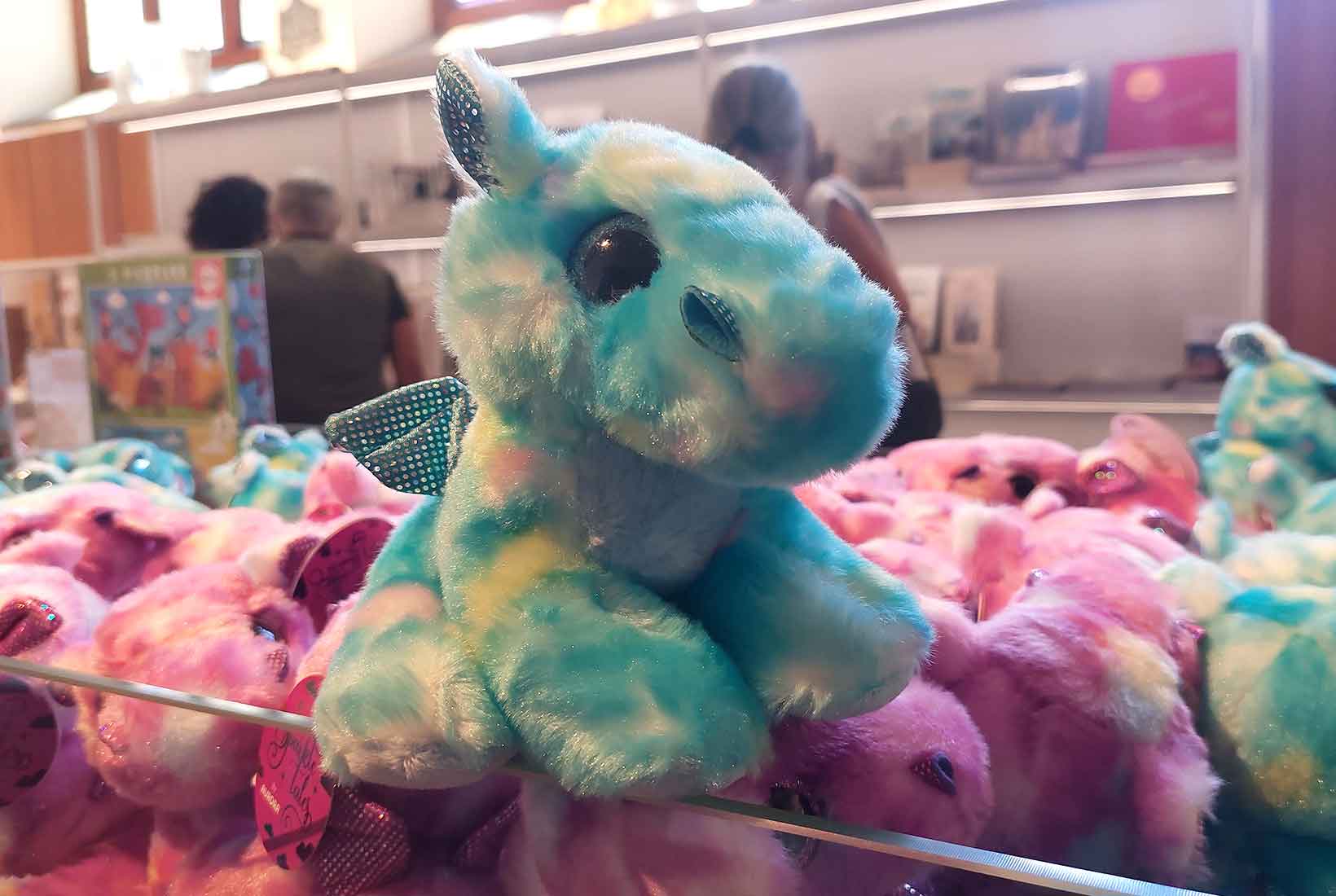 Peluche de dragón azul sobre un expositor en la tienda de Museo Gaudí Casa Botines en León.