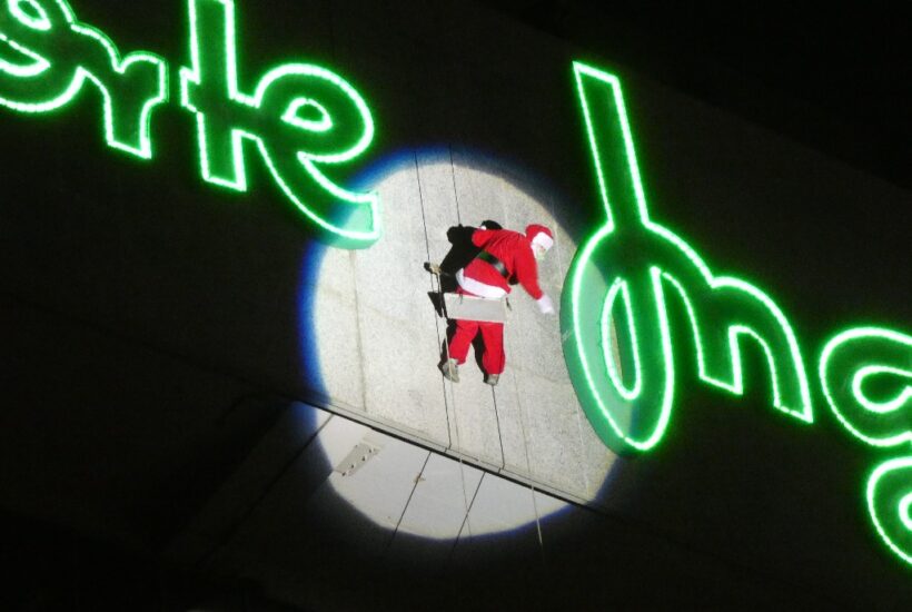 Papá Noel desciende colgado por la fachada de El corte Inglés de León iluminado por un foco