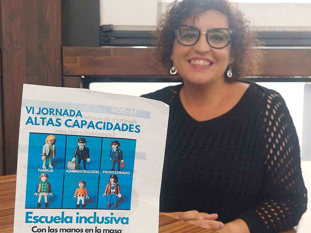 La maestra Susana Morán posa detrás del cartel de la VI Jornada de Altas Capacidades de León