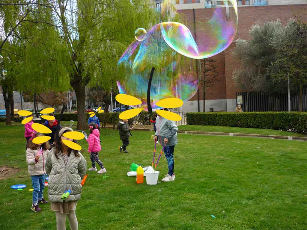 Niños y niñas juegan en un parque con grandes pompas de jabón en el campamento de Bill y Lula.