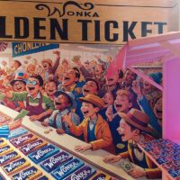 Puesto de chocolatinas Wonka junto a un gran cartel con la misma representación en la exposición sobre Tim Burton del Museo Munic en Carracedelo.