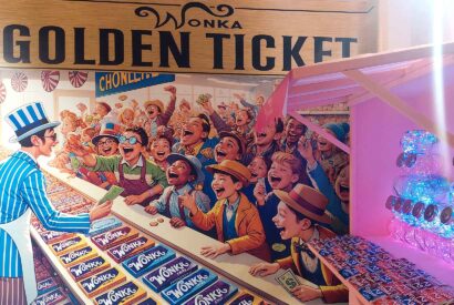Puesto de chocolatinas Wonka junto a un gran cartel con la misma representación en la exposición sobre Tim Burton del Museo Munic en Carracedelo.