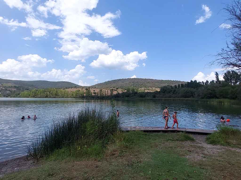 Varias personas pasean por una pasarela junto al Lago de Carucedo