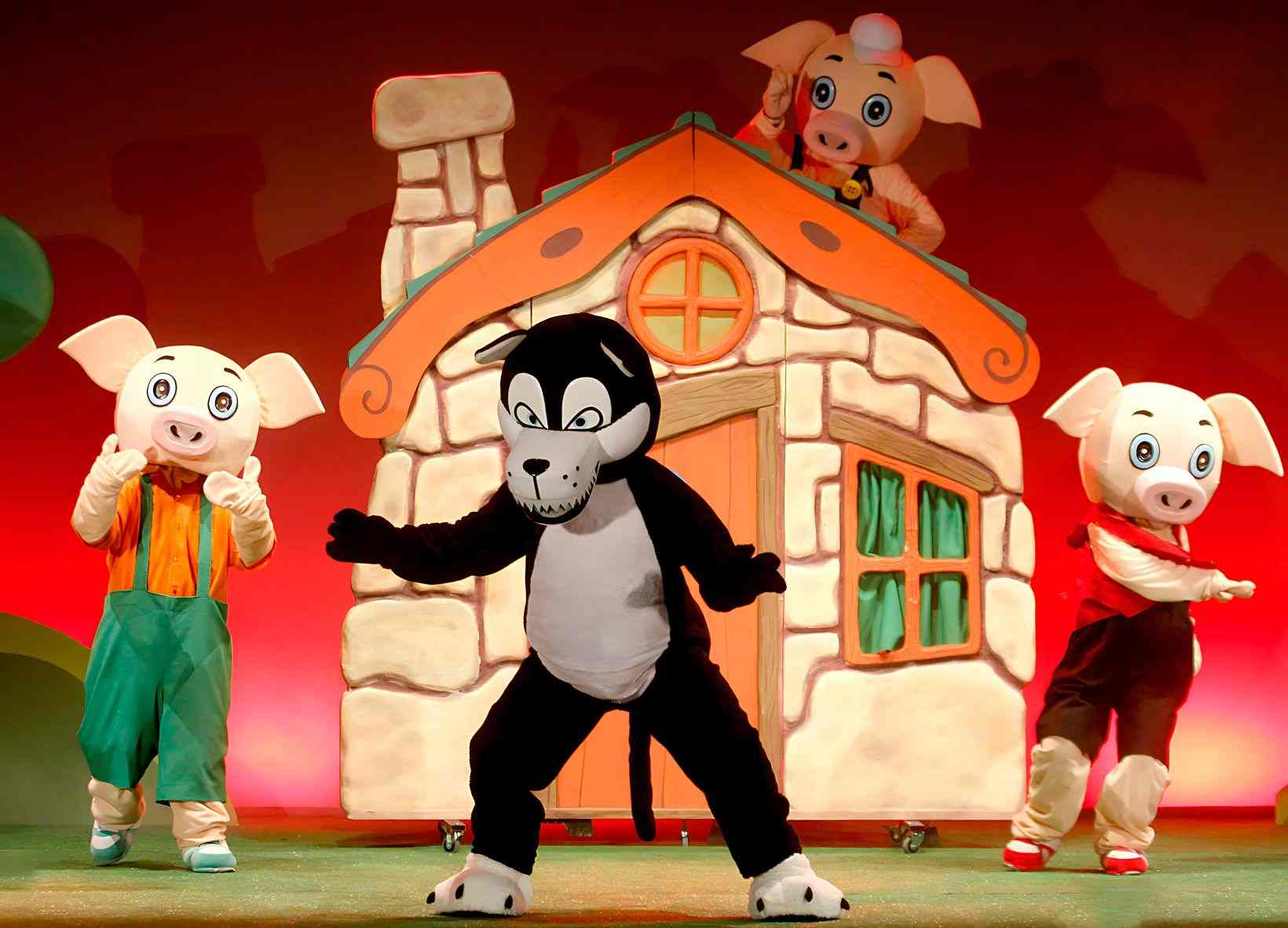 Personajes de la obra Los tres cerditos. Aparece el lobo y detrás de él los tres cerditos junto a la casa de ladrillos.