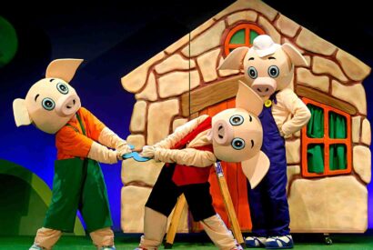 Los personajes de Los tres cerditos delante de la casa de ladrillo.