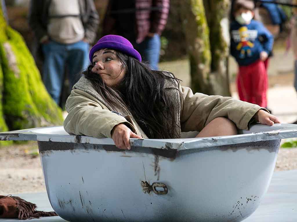 Una actriz con sombrero morado dentro de una bañera en plena actuación