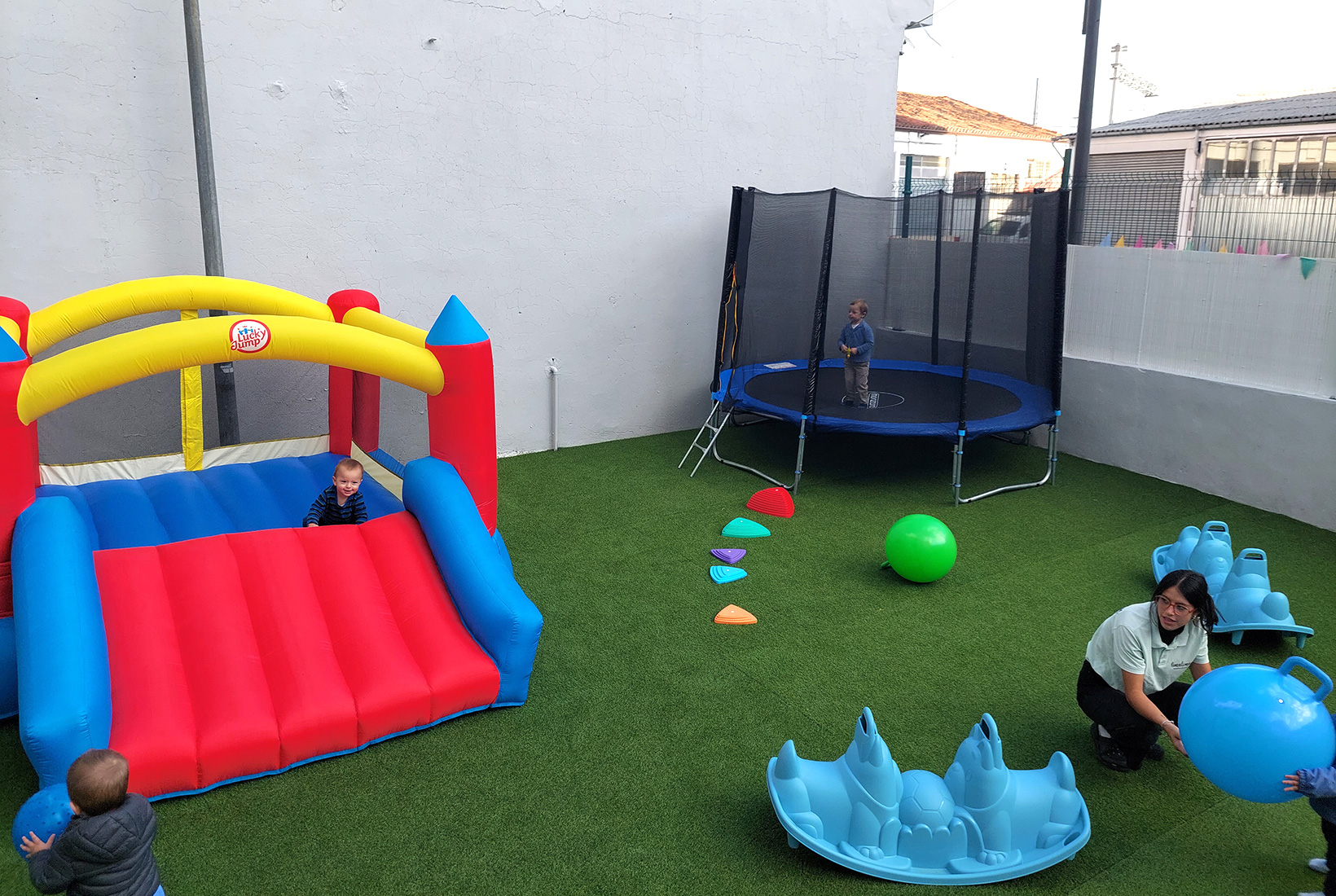 Varios niños juegan en el patio de Limalimón, cafetería para familias en León, en un castillo hinchable y una cama elástica bajo el cuidado de una monitora.