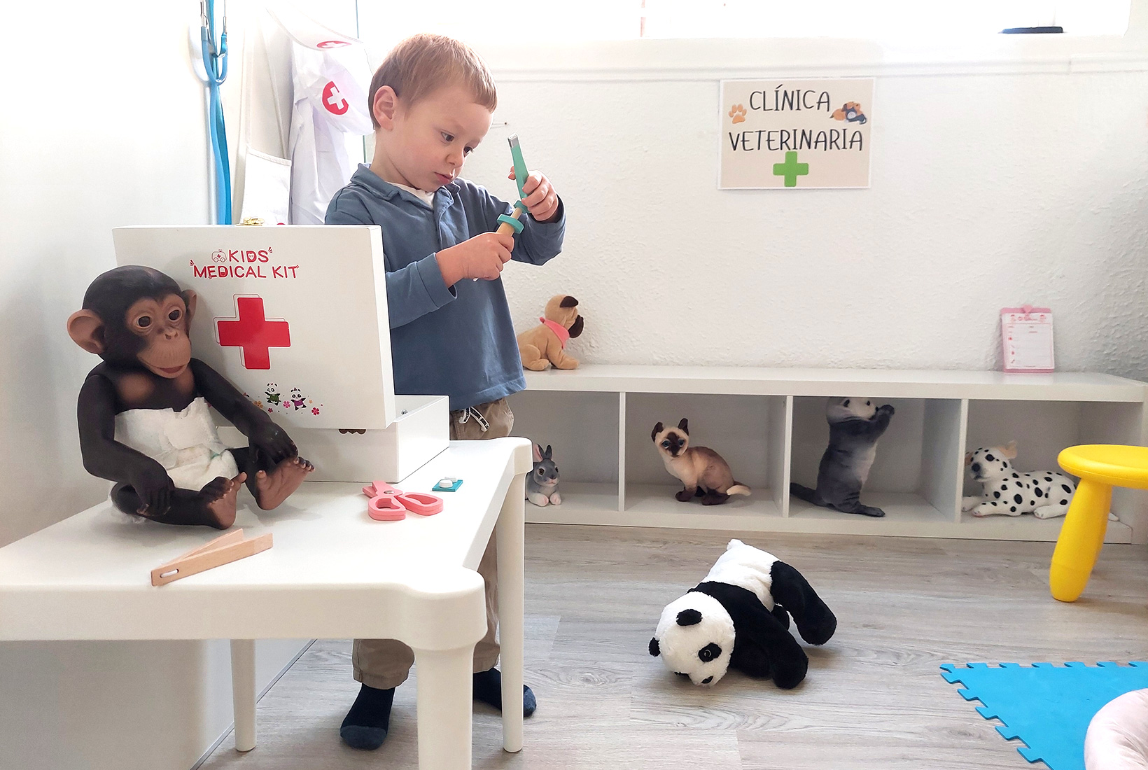 Un niño juega con juguetes de un kit de veterinario junto a varios peluches de animales en Limalimón, cafetería para familias en León.