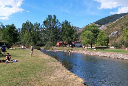 Varias personas se bañan en el río Curueño en la playa fluvial de Lugueros