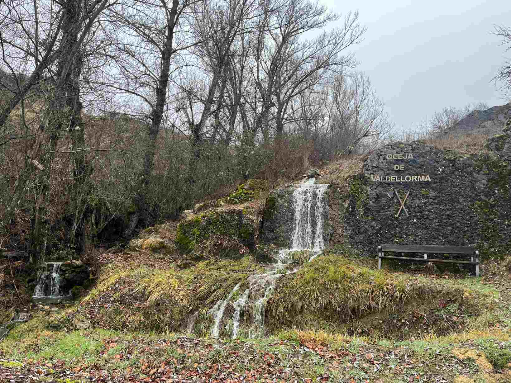 Cascada junto a un banco y unas letras que dicen Oceja de Valdellorma en la Senda Interactiva del Mamut, en esta localidad. 