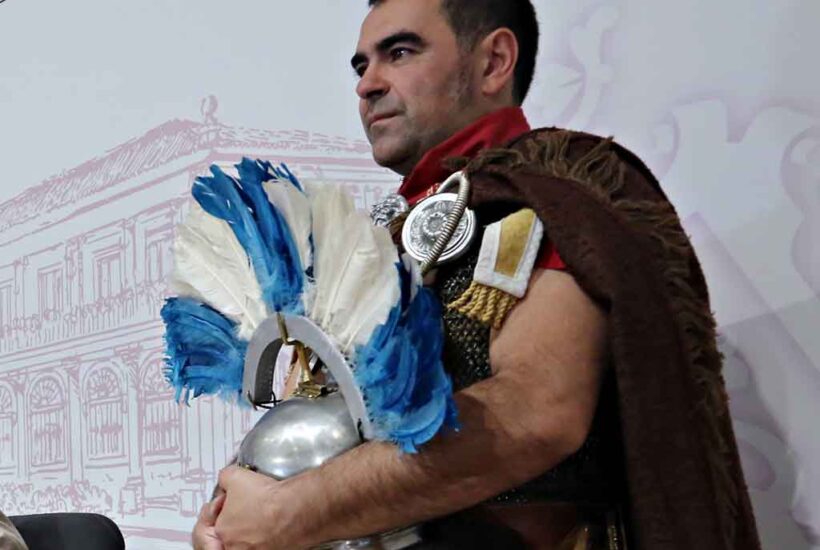 Un hombre vestido de romano con su casco en la mano para anunciar las actividades del Natalico de Águila en León