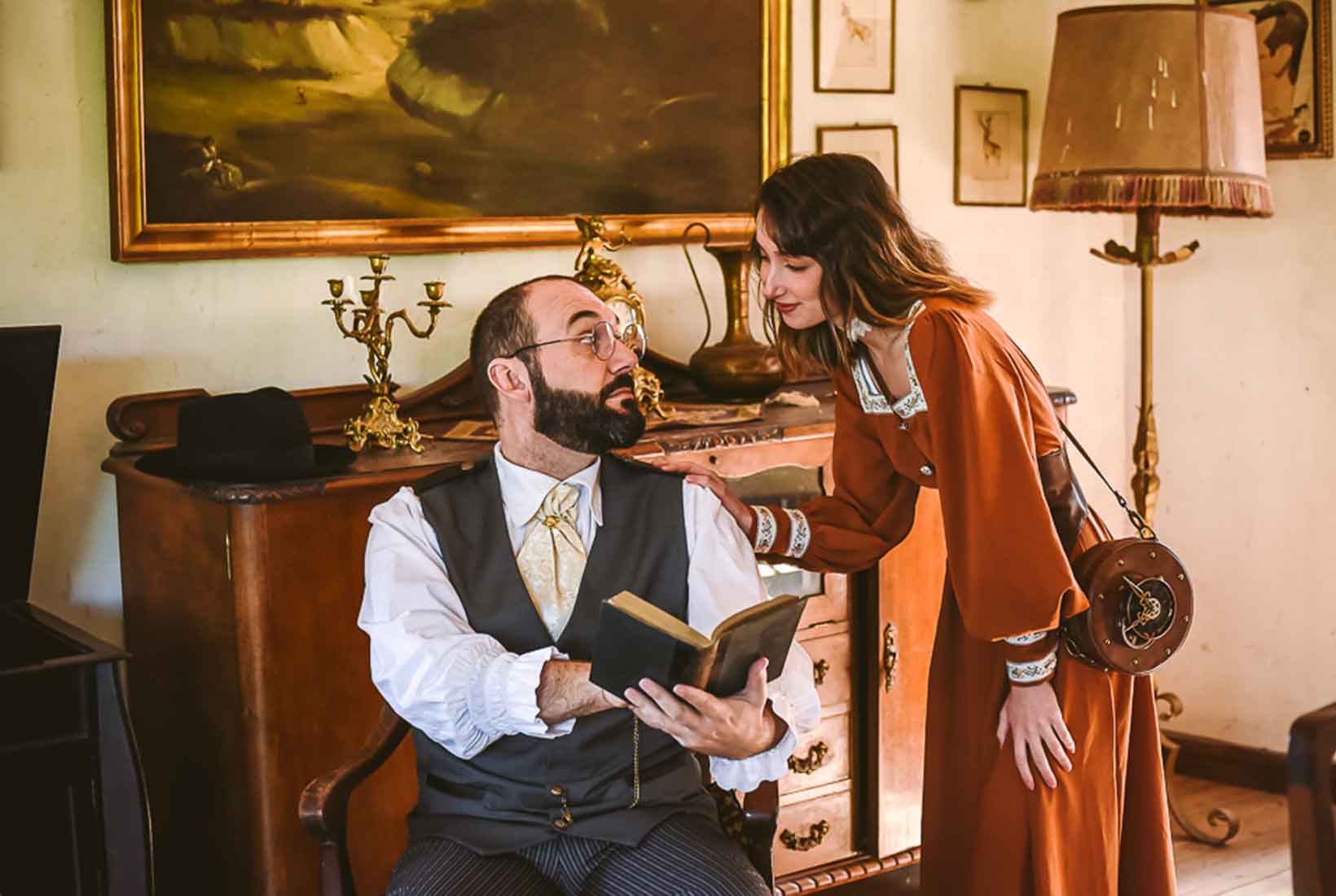 Una mujer apoya su mano sobre un hombre que le señala algo en un libro durante la representación teatral en la visita a El Soto de Villar