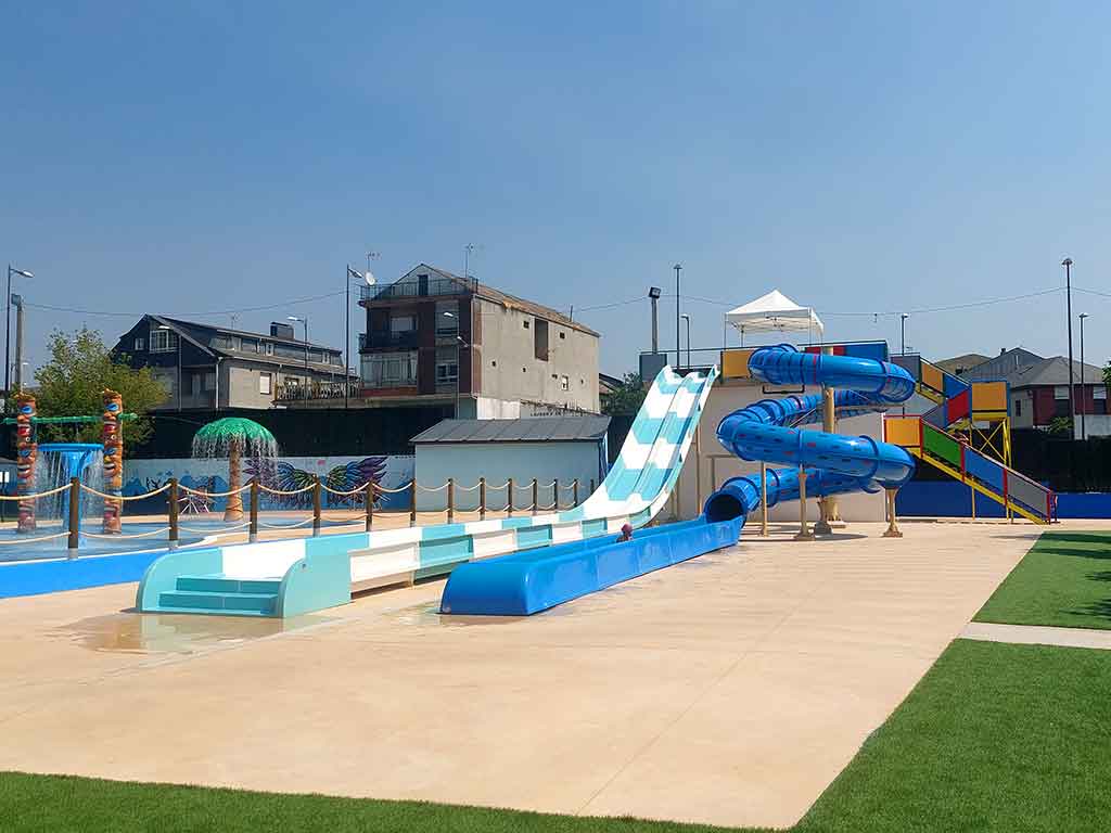 Toboganes de agua en la piscina de Toral de los Vados y zona de juegos al fondo